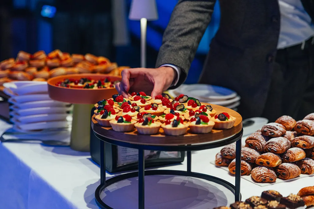 Buffet con pasticceria, crostatine alla frutta e vassoi serviti